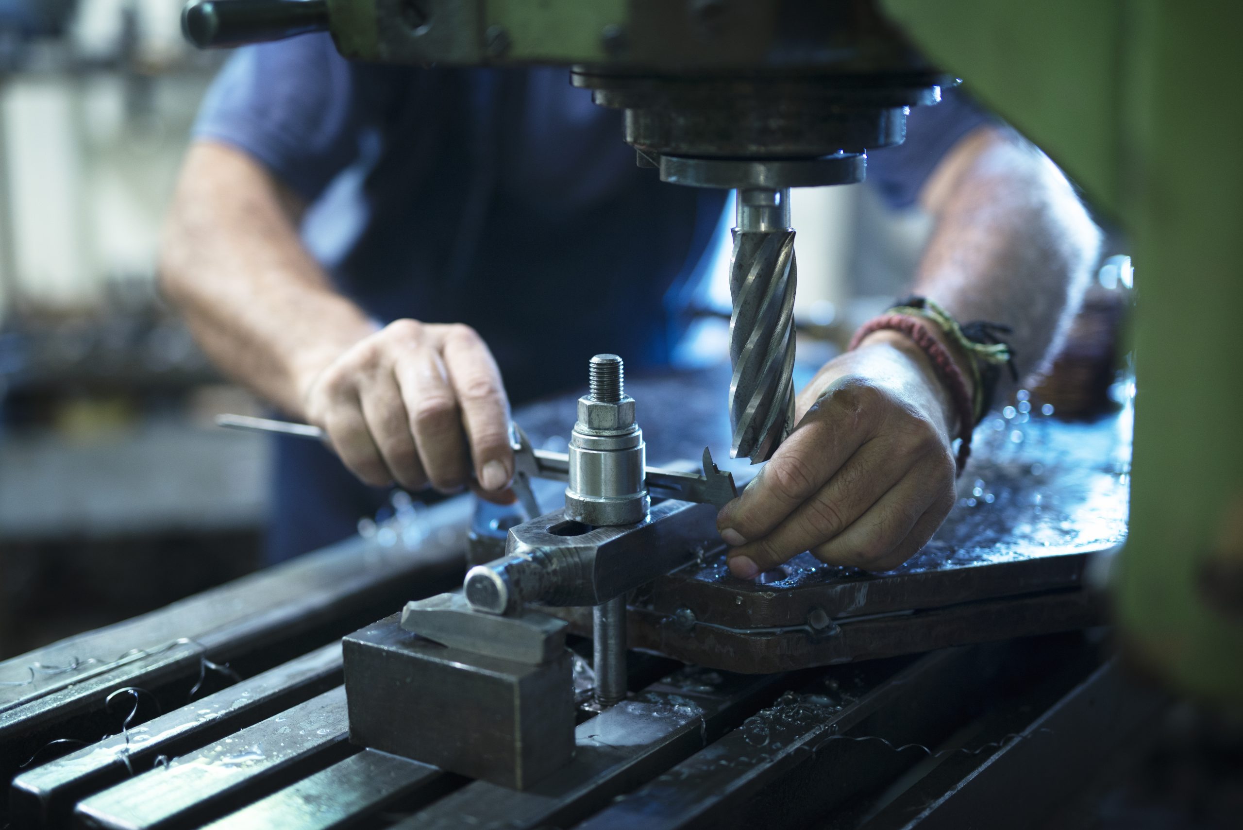Pneumatic Tools worker operating industrial machine in metal workshop.